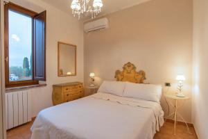 Un dormitorio con una cama blanca y una ventana. en Golden View Apartment with pool, en Castiglioncello