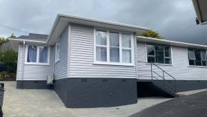 uma casa branca com duas janelas e uma entrada em Comfy & Sunny home in Wellington em Wellington
