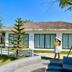 Private Villa في Phumĭ Prêk Chrey: امرأة ترتدي قبعة تقف أمام المنزل