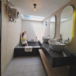 uma mulher sentada num balcão numa casa de banho com dois lavatórios em Private Villa em Phumĭ Prêk Chrey