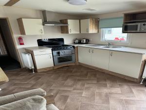 a kitchen with white cabinets and a stove top oven at Captivating 3-Bed Cabin in Prestonpans in Prestonpans