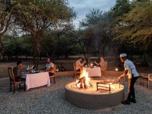 een groep mensen die aan tafels zitten rond een vuurplaats bij Sable Ranch Bush Lodge in Brits