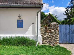 una casa bianca con una porta blu e una recinzione di Henye Vintage Home a Káli-medencében a Balatonhenye