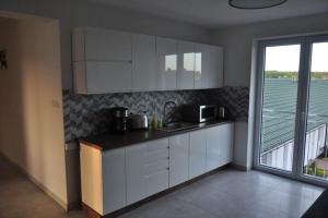 a kitchen with white cabinets and a large window at Holiday room for 3 people, Grzybowo in Grzybowo