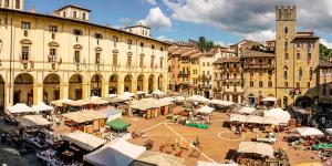 una plaza de la ciudad con mesas y sombrillas frente a los edificios en Grey House, en Arezzo