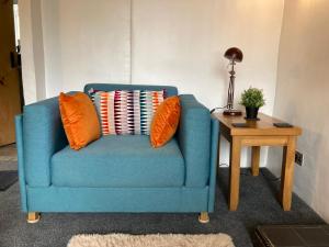 a blue chair with orange pillows sitting next to a table at Leven's Rest - 2 Bed Maisonette in Backbarrow