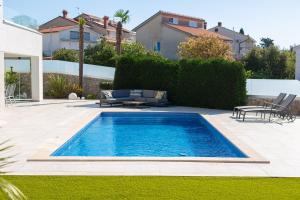 a swimming pool in a yard with chairs and a table at Villa Sia in Krk