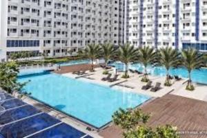 a large swimming pool with palm trees and a large building at 39th Flr Condo Unit with View in Manila