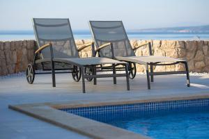 two lawn chairs sitting next to a swimming pool at Villa Sia in Krk +42 photos