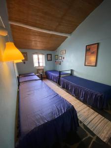 a room with three beds with blue sheets in it at Rosa Mar in Cabeça de Carneiro