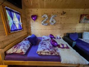a room with a bed with purple pillows and a number two at Cottage La Sierra with JACUZZI in Korenica