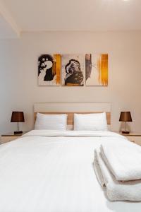 ein Schlafzimmer mit einem weißen Bett mit drei Gemälden an der Wand in der Unterkunft VESTA - Cairo Festival City Residence in Kairo