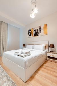 a white bedroom with a large white bed and a chandelier at VESTA - Cairo Festival City Residence in Cairo