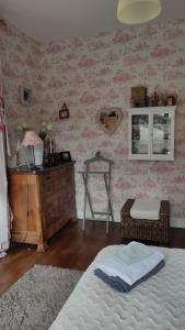 ルマンにあるCecileのピンクの壁紙のベッドルーム、ベッド1台、ドレッサーが備わります。