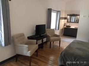 a room with two chairs and a television and a bed at la maison de Valbois in Varvinay