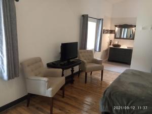 a room with two chairs and a television and a bed at la maison de Valbois in Varvinay +12 photos