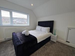 a bedroom with a bed and a large window at Modern Detached 3 bedroom home with off-road parking & bike store in Abercanaid