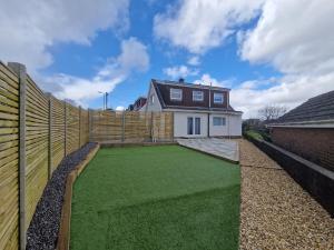 a backyard with a fence and a green lawn at Modern Detached 3 bedroom home with off-road parking & bike store in Abercanaid