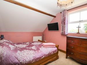 a bedroom with a bed and a tv and a dresser at The Old Chapel in Bawdeswell