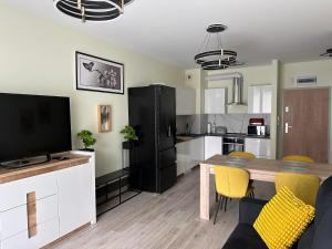 a kitchen and living room with a dining table and a television at Warmia Loft Apartament nad Iławką in Iława