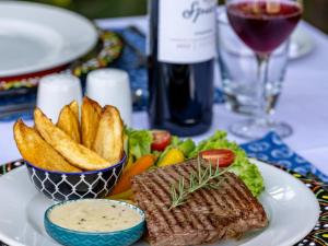 um prato com carne e batatas fritas e um copo de vinho em Sable Ranch Bush Lodge em Brits