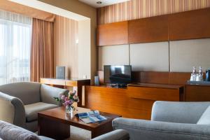 een woonkamer met 2 stoelen en een televisie bij Regardal Hotel in Alma-Ata