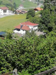 uma casa com um telhado vermelho atrás de algumas árvores em Ferienwohnung Reinstadler Ilse em Jerzens