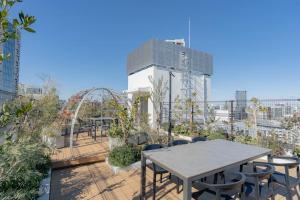 een patio met tafels en stoelen bovenop een gebouw bij unito residence HIGASHISHINJUKU in Tokyo