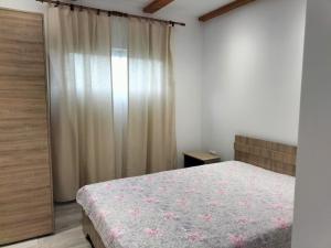 a bedroom with a bed and a window with curtains at Casa Emma in Vişeu de Jos