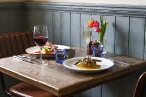 a wooden table with two plates of food and wine glasses at The Swan at Forest Row in Forest Row