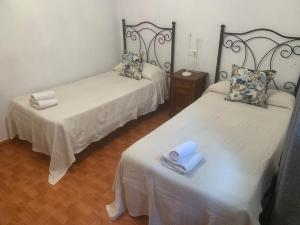 two beds with towels on them in a room at Apartamentos La Mina de Viñón. in Santa Eulalia