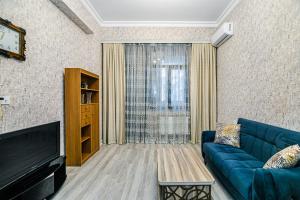 Deluxe Apartment 128/34 في باكو: غرفة معيشة بها أريكة زرقاء وتلفزيون
