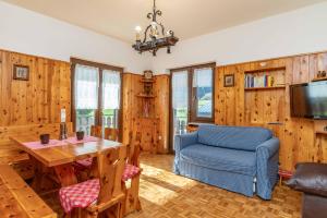 een woonkamer met houten muren en een blauwe stoel en een tafel bij Trilo Luce della Paganella in Andalo