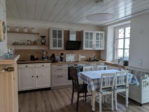 eine Küche mit weißen Schränken, einem Tisch und Stühlen in der Unterkunft Stefans Stadthaus in Saarburg