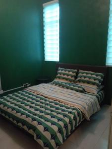 a green bedroom with a bed with two pillows at D'Alessa Homestay in Alor Setar