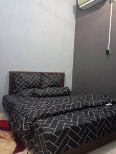 a bed with a black and white comforter and pillows at D'Alessa Homestay in Alor Setar