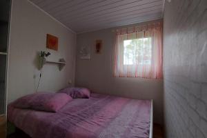 łóżko w sypialni z oknem w obiekcie Domek 4 -os Szwedzki w Campark Service "Zielony Zakątek" w mieście Mrągowo