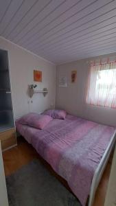 sypialnia z łóżkiem z fioletową pościelą i oknem w obiekcie Domek 4 -os Szwedzki w Campark Service "Zielony Zakątek" w mieście Mrągowo