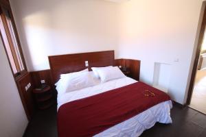 una camera da letto con un grande letto con lenzuola rosse e bianche di Villa Tizra - guest house a AÃ¯n el Ksob