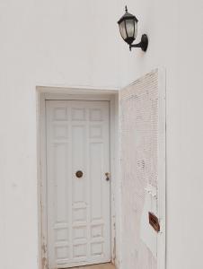 a white door in a white wall with a lamp at Bella casa in Tataouine
