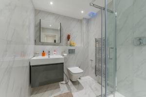 La salle de bains est pourvue de toilettes, d'un lavabo et d'une douche. dans l'établissement Modern Elegance 1 Bedroom City Living in London 5, à Londres