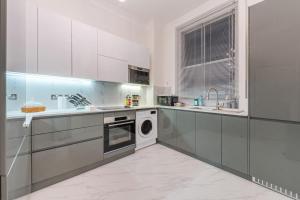 a kitchen with white cabinets and a dishwasher at Modern Elegance 1 Bedroom City Living in London 5 in London