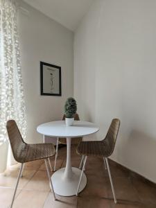 a white table with two chairs and a vase on it at A CASA ROSSA , La Marjolaine in Saint Paul de Vence
