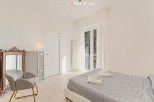 um quarto branco com uma cama e uma cadeira em Giuly House, Terre Marine em Le Grazie