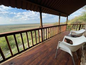 un porche con una silla blanca en una terraza de madera en Aloegrove Safari Lodge en Otjiwarongo