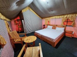 um quarto com uma cama, uma mesa e cadeiras em Hipostel Bir - Stay and Cafe em Bir
