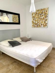 - un lit blanc dans une chambre avec une photo sur le mur dans l'établissement Appartement centre ville - 4p, à LʼÎle-Rousse
