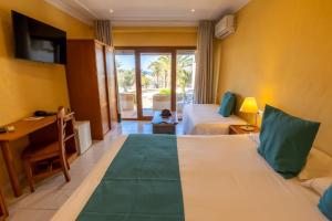 a hotel room with two beds and a desk and a television at Hotel Club Sunway Punta Prima in Es Pujols