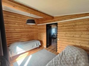 a bedroom with wooden walls and two beds in a room at Villa Lahnajärvi in Salo