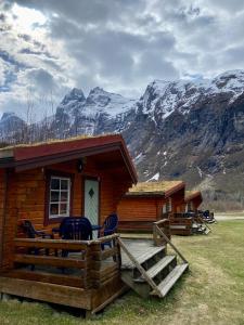 una cabaña de madera con montañas al fondo en Trollstigen Camping and Gjestegård, en Åndalsnes